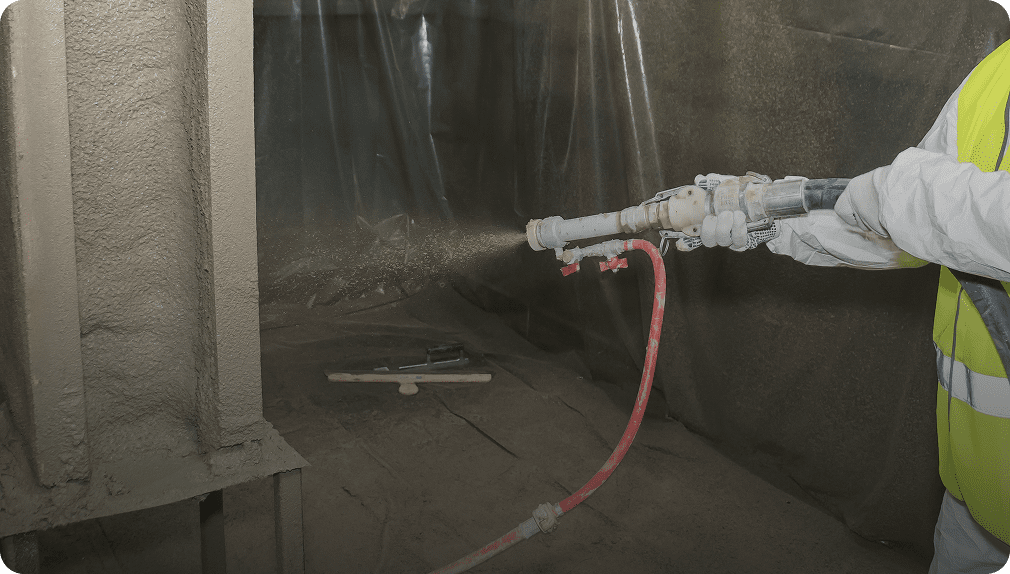 Worker spraying insulation in construction area.